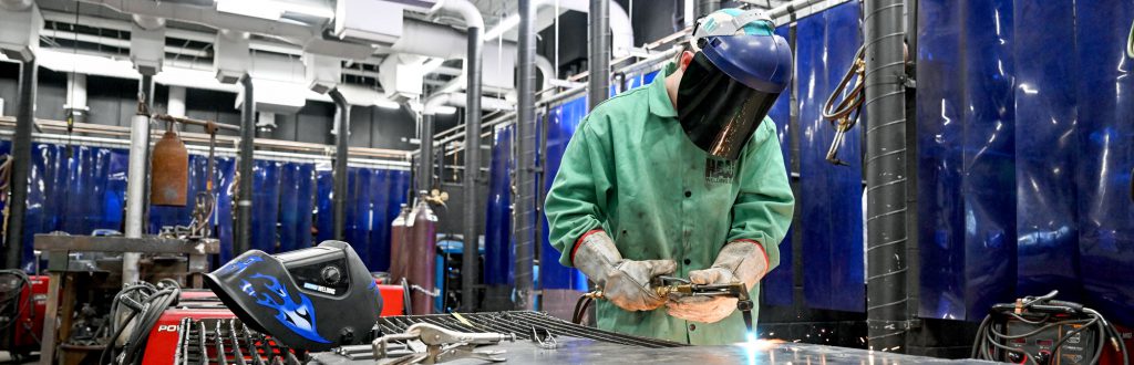 Student welding in metal work shop