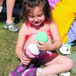 A young student plays outdoors with a large plastic ice cream cone toy.